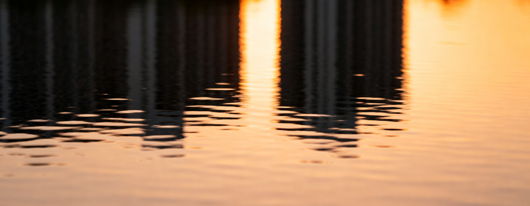 a reflection of buildings on water during sunset